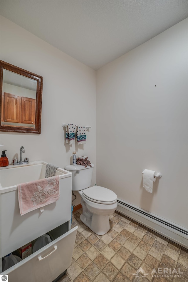 bathroom with toilet, sink, and a baseboard heating unit