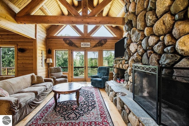 living room featuring beam ceiling, a stone fireplace, high vaulted ceiling, and light hardwood / wood-style flooring