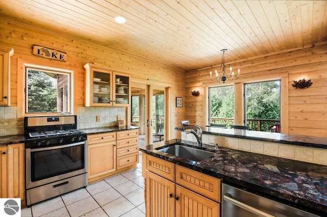 kitchen with sink, appliances with stainless steel finishes, a wealth of natural light, light tile patterned flooring, and decorative light fixtures