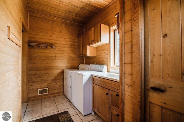 washroom featuring light tile patterned floors, wood ceiling, wooden walls, cabinets, and washing machine and clothes dryer