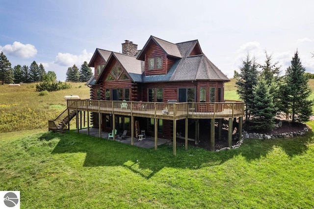 rear view of house with a wooden deck, a patio, and a lawn