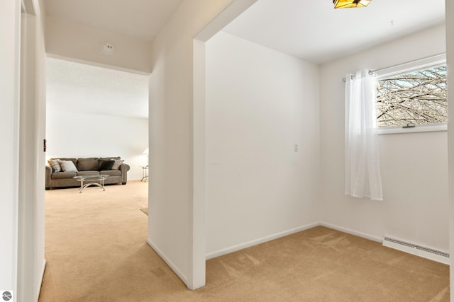 carpeted spare room featuring a baseboard heating unit