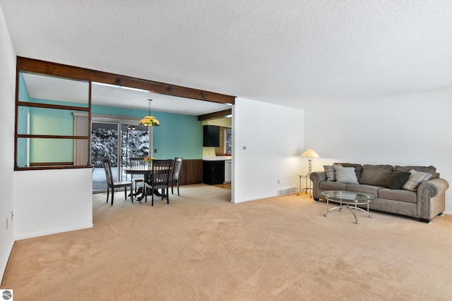 carpeted living room with beam ceiling and a textured ceiling