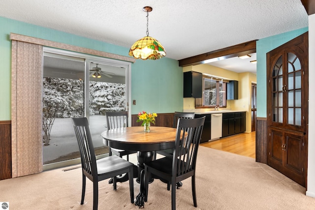 carpeted dining area with beam ceiling, sink, and a textured ceiling