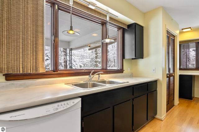 kitchen with hanging light fixtures, sink, white dishwasher, and light wood-type flooring