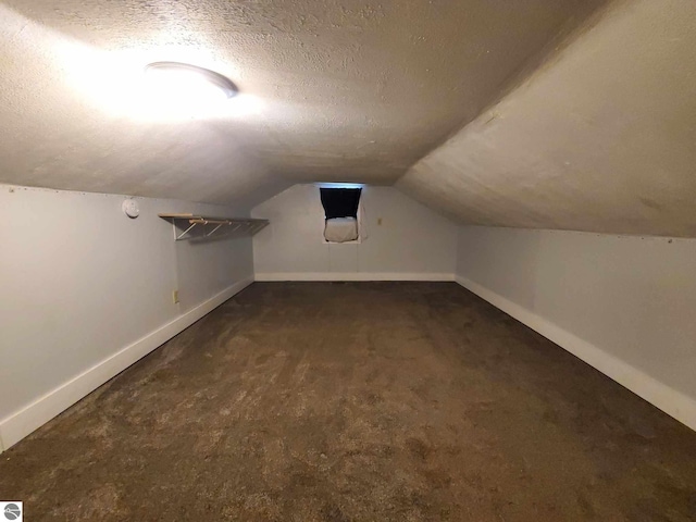 bonus room with vaulted ceiling, dark carpet, and a textured ceiling