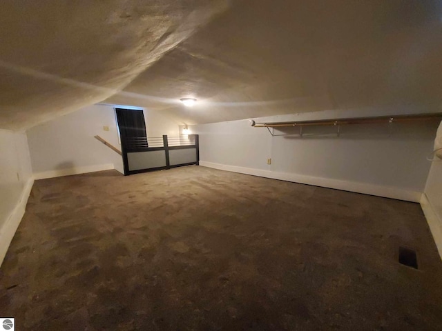 bonus room featuring lofted ceiling and dark colored carpet