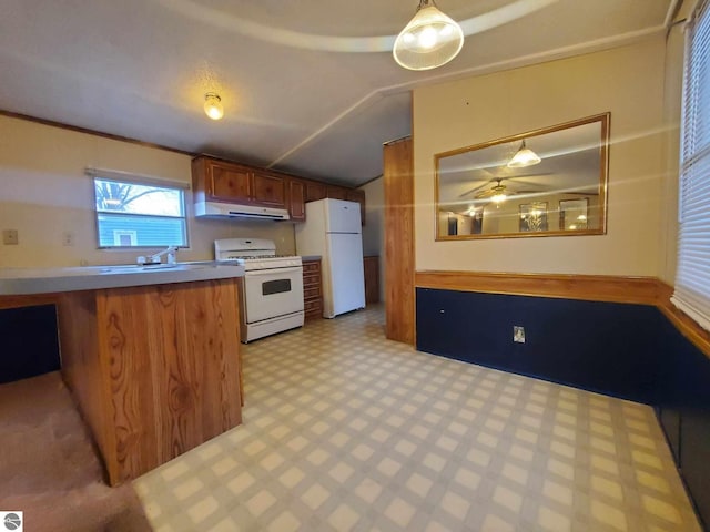 kitchen with hanging light fixtures, white appliances, vaulted ceiling, and sink