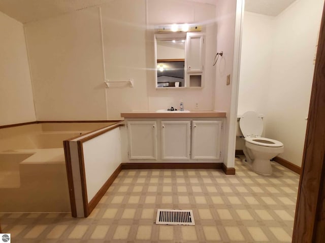 bathroom featuring toilet, vanity, and a bath