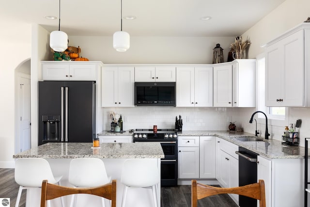 kitchen with white cabinets, sink, a kitchen island, and black appliances