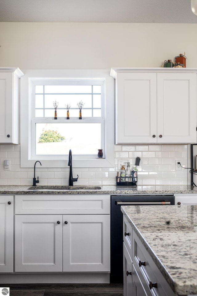 kitchen featuring sink, white cabinetry, light stone counters, dishwasher, and backsplash