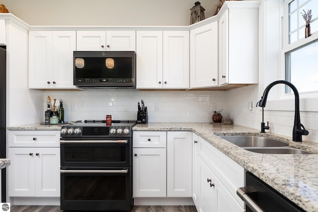 kitchen with range with two ovens, white cabinetry, and sink