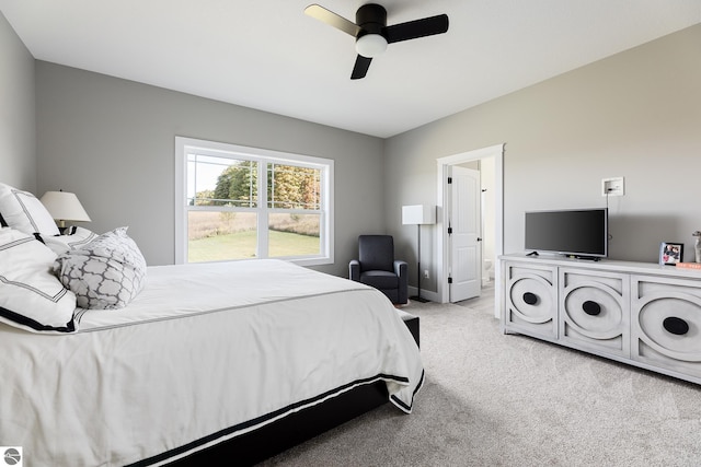 bedroom featuring ensuite bath, light colored carpet, and ceiling fan