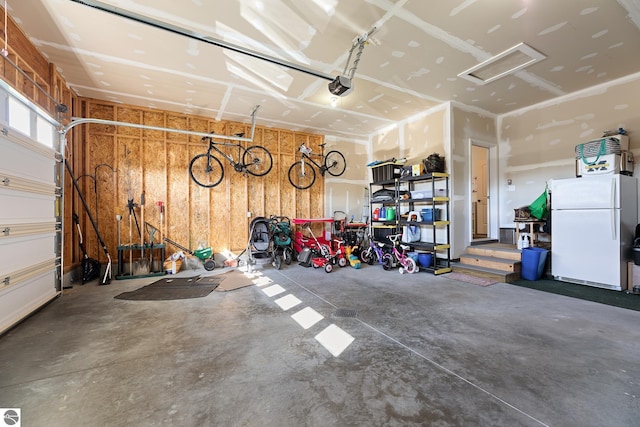 garage featuring a garage door opener and white fridge