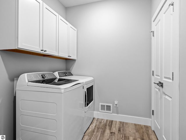 laundry room featuring cabinets, hardwood / wood-style floors, and independent washer and dryer