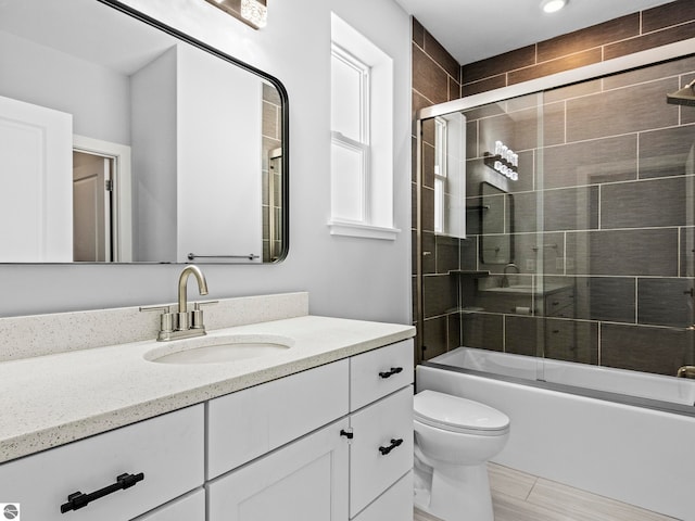 full bathroom featuring bath / shower combo with glass door, vanity, and toilet