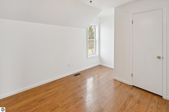 additional living space featuring vaulted ceiling and light wood-type flooring