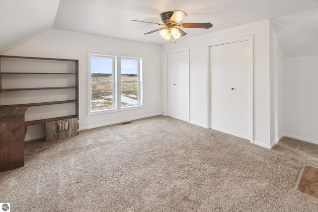 unfurnished bedroom with multiple closets, ceiling fan, lofted ceiling, and carpet floors