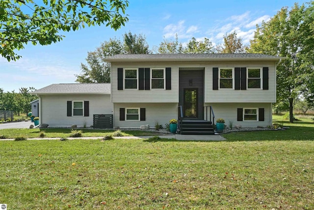 raised ranch with cooling unit and a front lawn