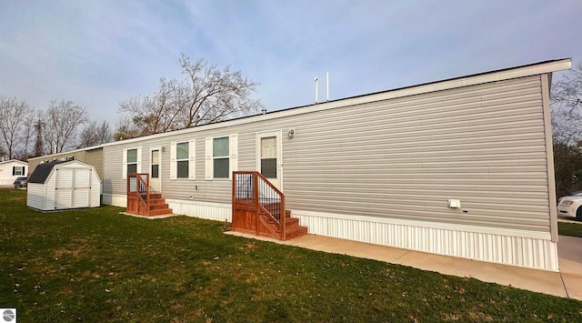 back of house featuring a lawn and a storage unit