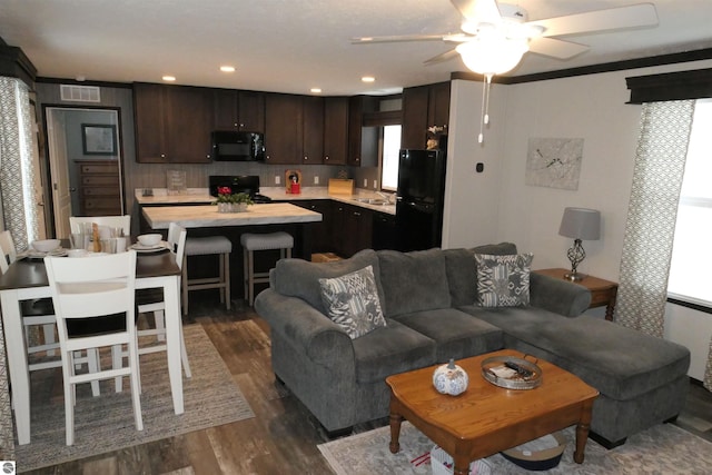 living room with a healthy amount of sunlight, dark wood-type flooring, sink, and ceiling fan