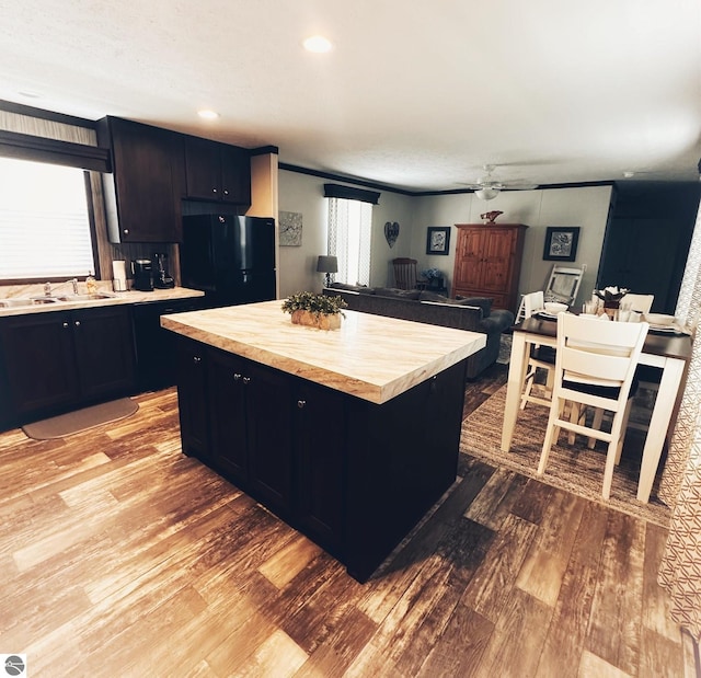 kitchen with black refrigerator, light hardwood / wood-style floors, sink, and a kitchen island