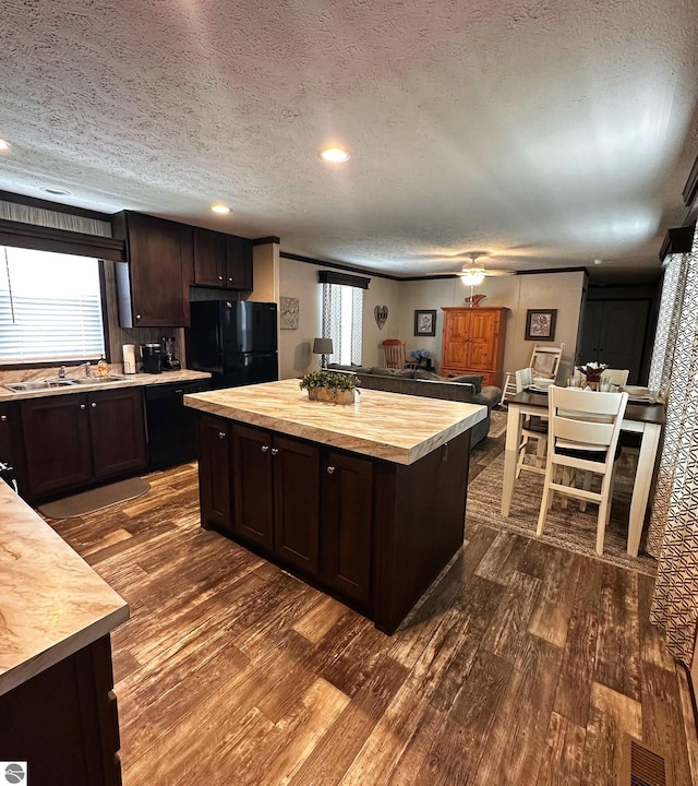 kitchen with dark hardwood / wood-style floors, butcher block countertops, a center island, black appliances, and dark brown cabinets