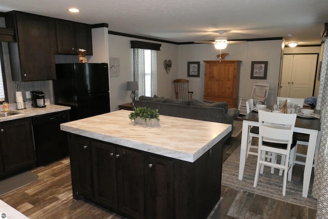 kitchen featuring crown molding, dark hardwood / wood-style flooring, a kitchen island, and black appliances