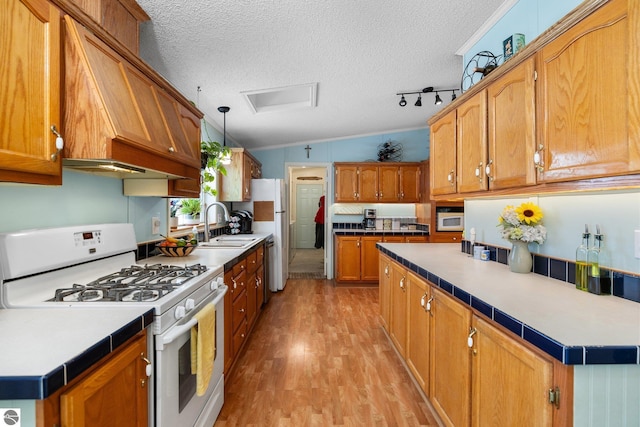 kitchen with pendant lighting, white appliances, light hardwood / wood-style flooring, and a textured ceiling