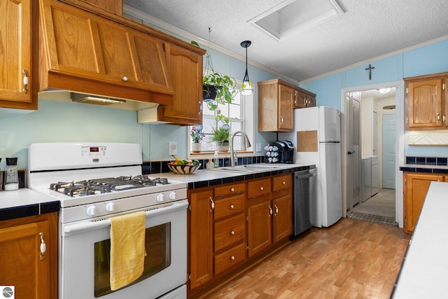 kitchen featuring sink, white appliances, hanging light fixtures, ornamental molding, and custom range hood