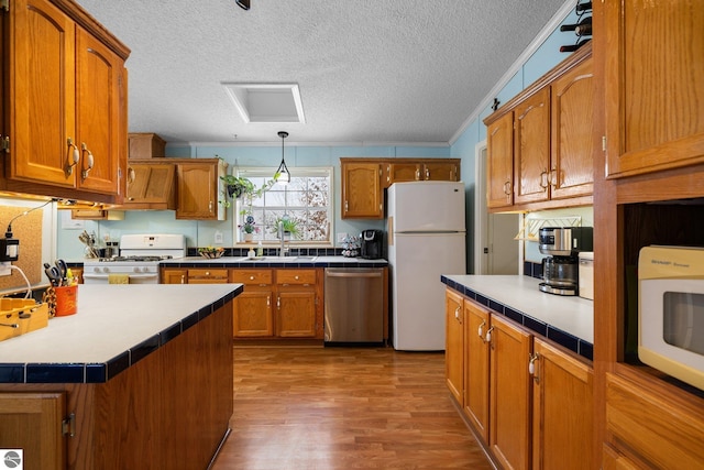 kitchen with decorative light fixtures, sink, white appliances, a textured ceiling, and light wood-type flooring