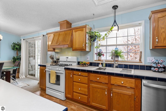 kitchen with pendant lighting, dishwasher, sink, white gas range oven, and plenty of natural light