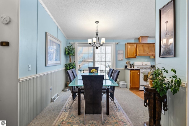 dining space with a notable chandelier, ornamental molding, light colored carpet, and a textured ceiling