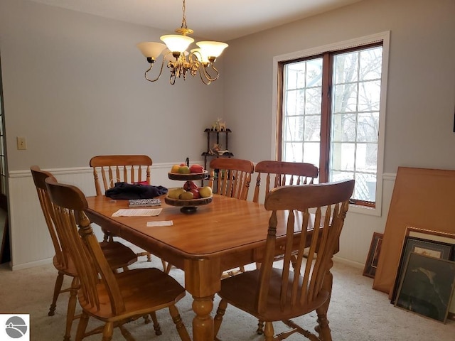 dining area with light carpet and a notable chandelier