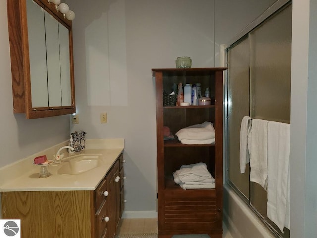 bathroom featuring shower / bath combination with glass door, baseboards, and vanity