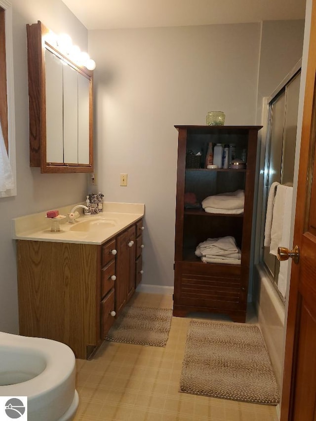 bathroom featuring baseboards, combined bath / shower with glass door, and vanity