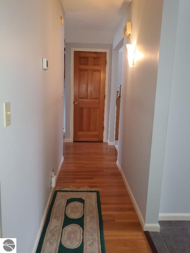 hall with baseboards and dark wood-type flooring