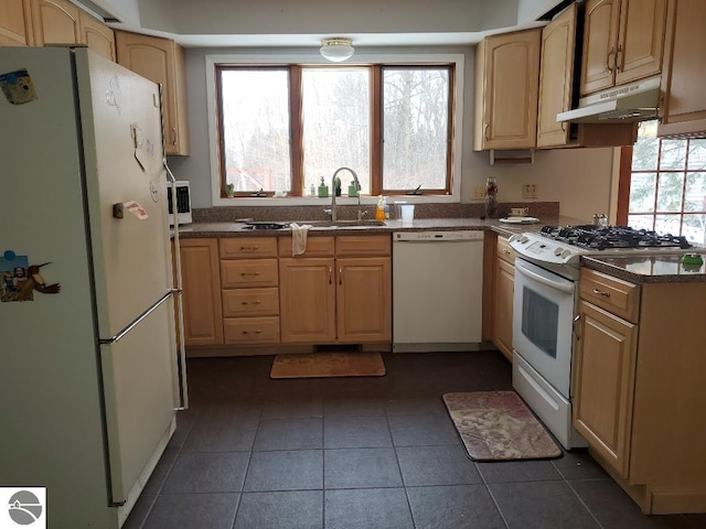 kitchen featuring white appliances, light brown cabinetry, sink, and dark tile patterned floors