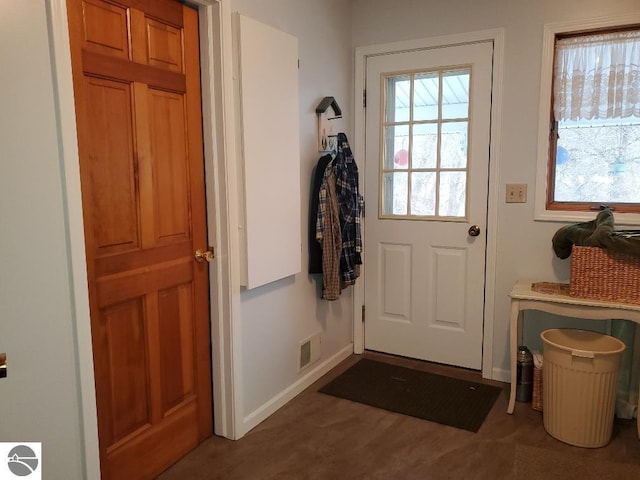 doorway to outside featuring baseboards, visible vents, and a healthy amount of sunlight