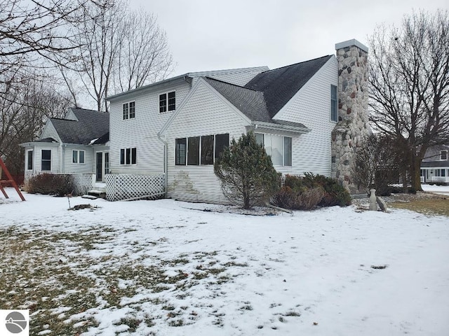 snow covered house featuring a chimney