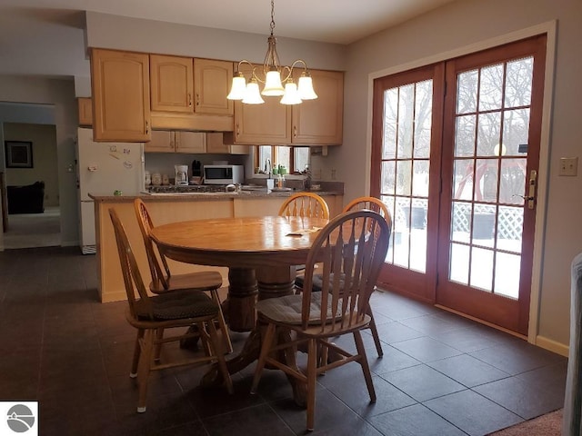 dining space with a chandelier and dark tile patterned floors