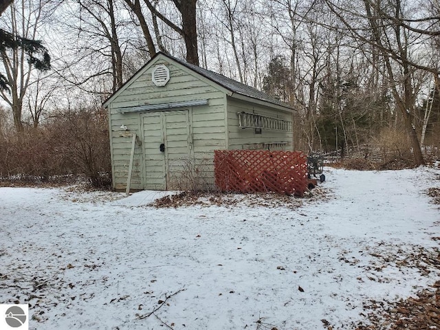 snow covered structure featuring a storage unit and an outdoor structure