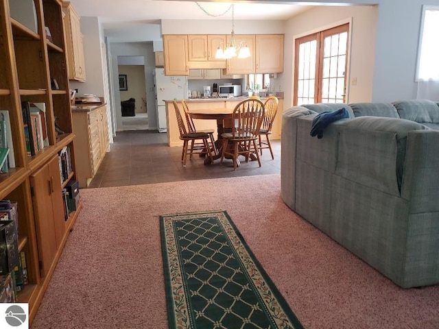 dining room with dark tile patterned floors, dark carpet, and a notable chandelier