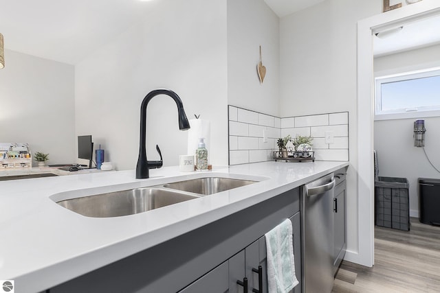 kitchen featuring dishwasher, sink, light wood-type flooring, and decorative backsplash