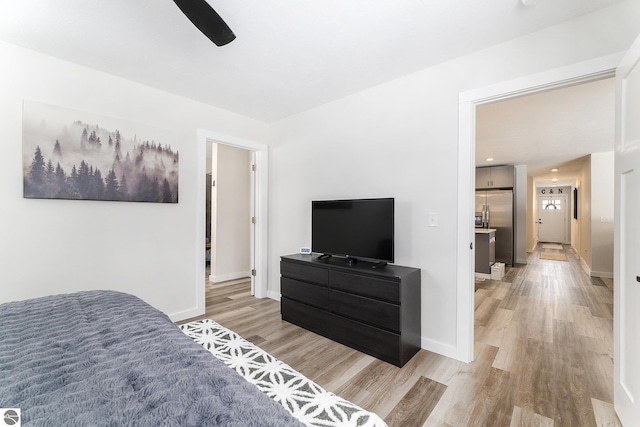 bedroom featuring stainless steel fridge with ice dispenser, light hardwood / wood-style flooring, and ceiling fan