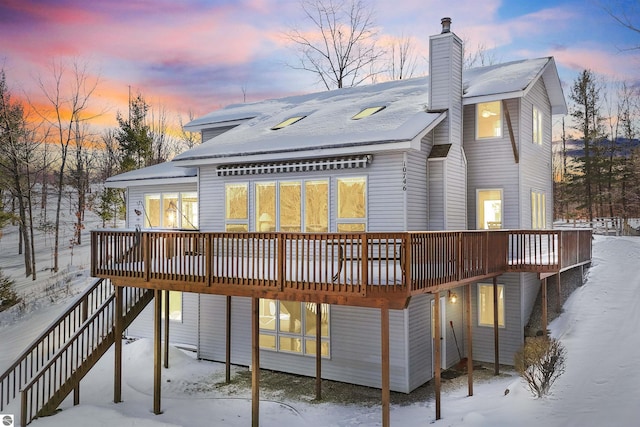 snow covered back of property with a wooden deck