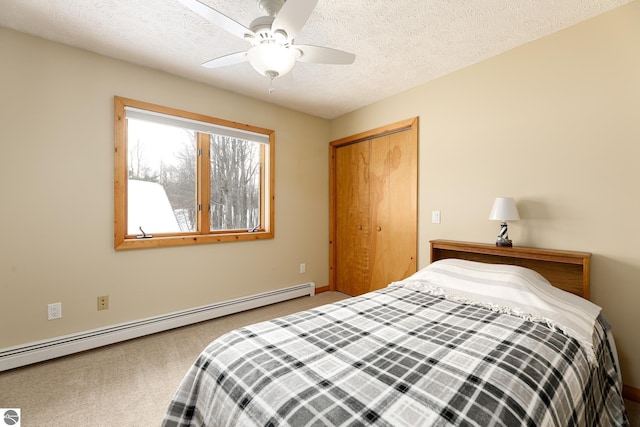 carpeted bedroom with baseboard heating, ceiling fan, a closet, and a textured ceiling