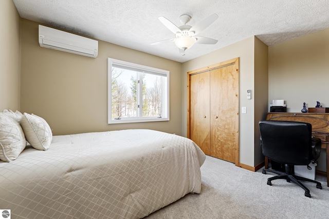 bedroom featuring a wall unit AC, a closet, a textured ceiling, and carpet flooring