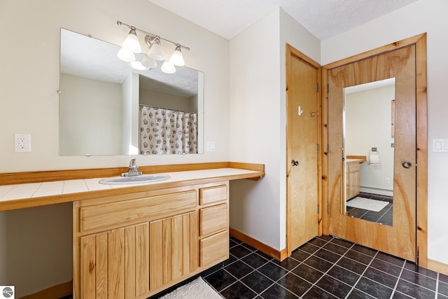 bathroom with tile patterned floors, vanity, a textured ceiling, and a baseboard heating unit