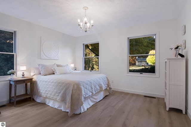 bedroom with an inviting chandelier and light hardwood / wood-style floors